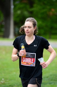 A marathoner holds a bottle of honey while she runs